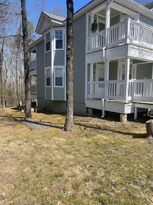 back of property with a lawn and a balcony