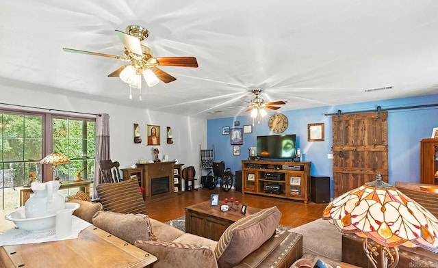 living room featuring ceiling fan, a barn door, and hardwood / wood-style flooring