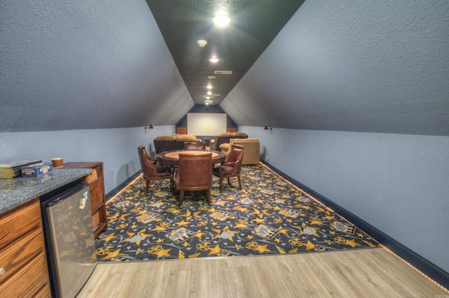 interior space with a textured ceiling, vaulted ceiling, and light hardwood / wood-style flooring