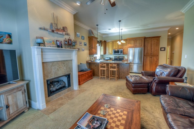 living room with ceiling fan, crown molding, and a tile fireplace