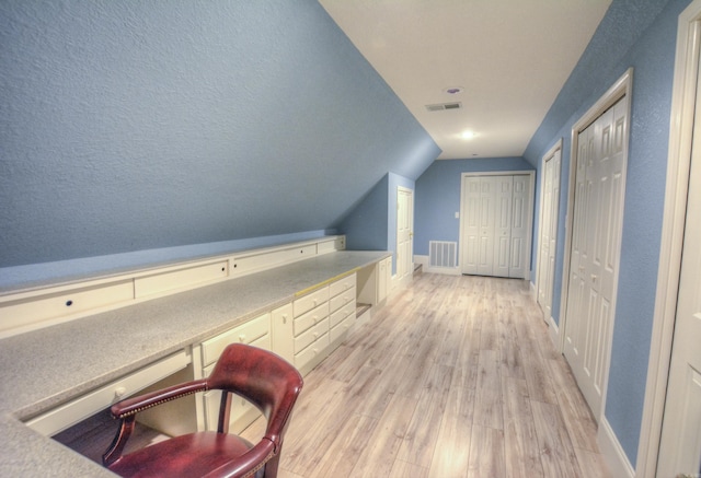 bonus room with a textured ceiling, vaulted ceiling, and light wood-type flooring