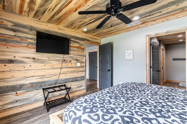 bedroom with ceiling fan, dark hardwood / wood-style floors, wood ceiling, and wooden walls