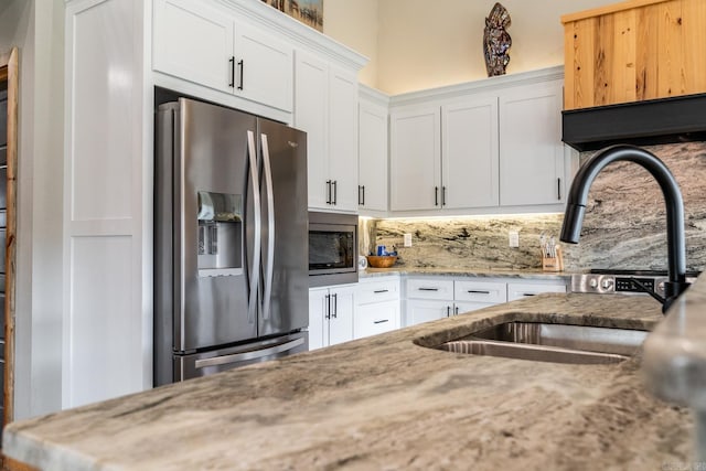 kitchen featuring appliances with stainless steel finishes, light stone countertops, white cabinetry, and backsplash