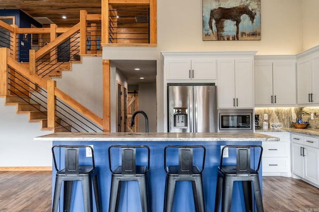 kitchen featuring dark hardwood / wood-style floors, white cabinetry, appliances with stainless steel finishes, and tasteful backsplash