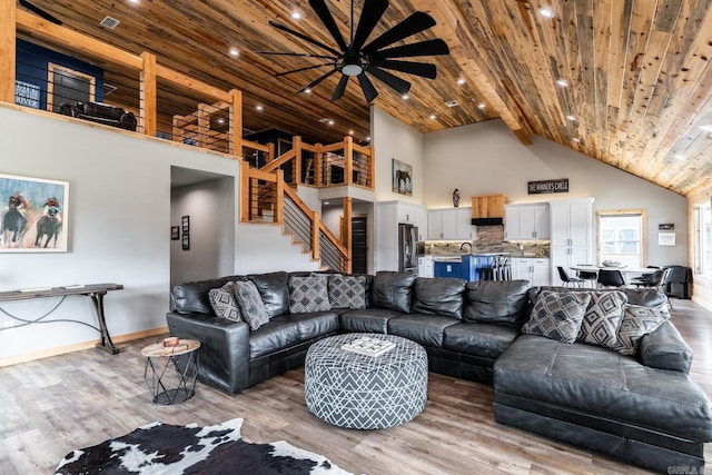 living room with wooden ceiling, ceiling fan, light wood-type flooring, and a towering ceiling