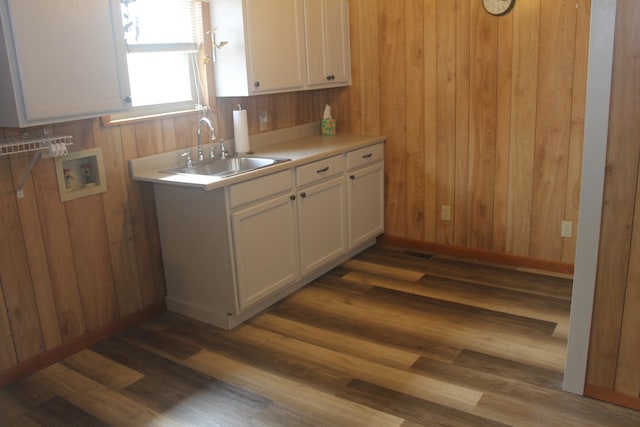 kitchen with sink, wooden walls, dark hardwood / wood-style floors, and white cabinets