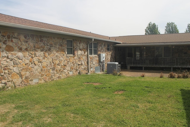 back of property featuring a yard and central AC