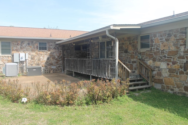 back of house with central AC unit and a lawn