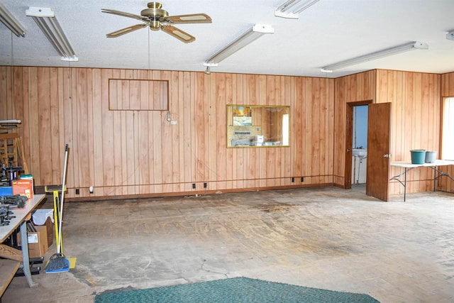 interior space featuring wooden walls, a textured ceiling, and ceiling fan