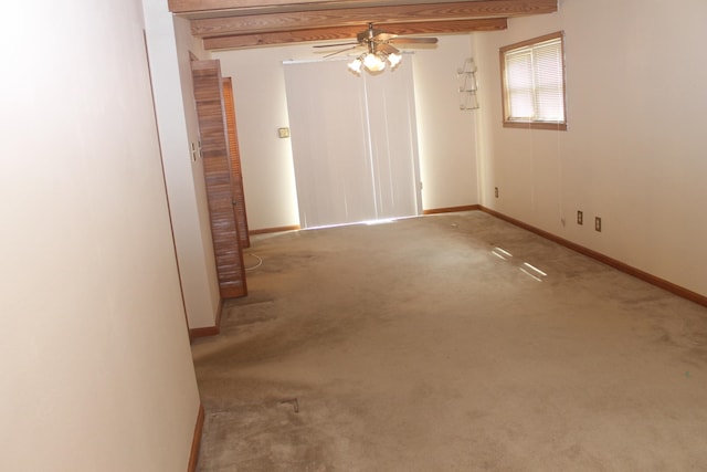 carpeted empty room with beam ceiling and ceiling fan