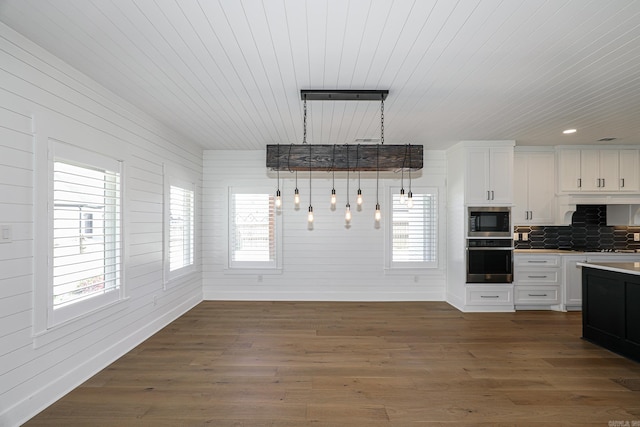 kitchen with stainless steel appliances, white cabinets, dark wood-type flooring, tasteful backsplash, and hanging light fixtures