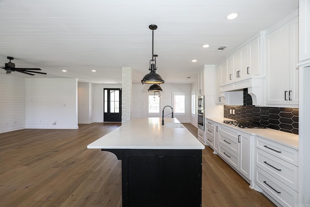 kitchen featuring dark hardwood / wood-style flooring, hanging light fixtures, plenty of natural light, and a center island with sink