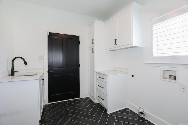 laundry room with hookup for a washing machine, electric dryer hookup, dark tile flooring, sink, and cabinets