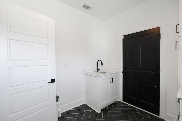 laundry area featuring dark tile floors and sink