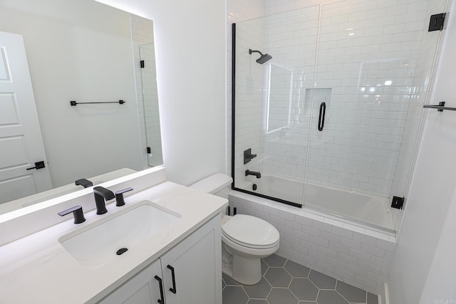 full bathroom featuring tile floors, toilet, vanity, and combined bath / shower with glass door