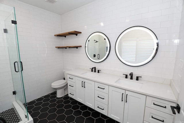 bathroom with tile floors, toilet, double sink, tile walls, and walk in shower