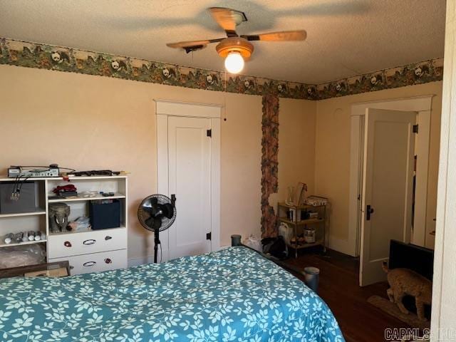 bedroom featuring dark hardwood / wood-style floors, ceiling fan, and a textured ceiling