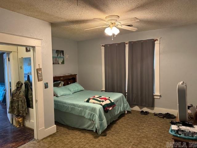 bedroom with a textured ceiling, ceiling fan, and dark wood-type flooring