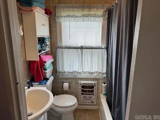 full bathroom with tile walls, sink, shower / bath combo, toilet, and tile floors