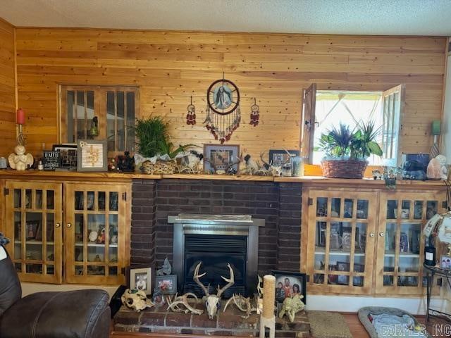 living room featuring wood walls, a textured ceiling, and a fireplace