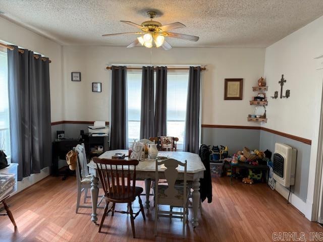 dining space with ceiling fan, light wood-type flooring, and a textured ceiling