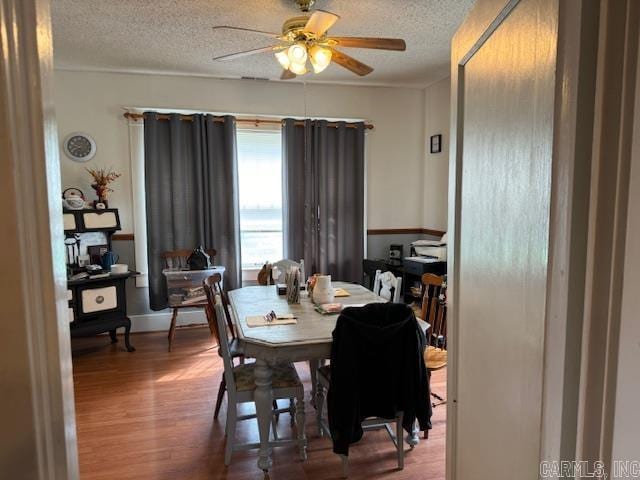 dining area with dark wood-type flooring, ceiling fan, and a textured ceiling