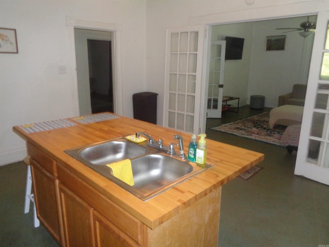 kitchen featuring butcher block countertops, a sink, and a ceiling fan