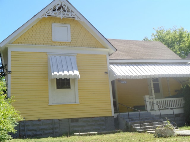 view of home's exterior featuring crawl space, a porch, and roof with shingles