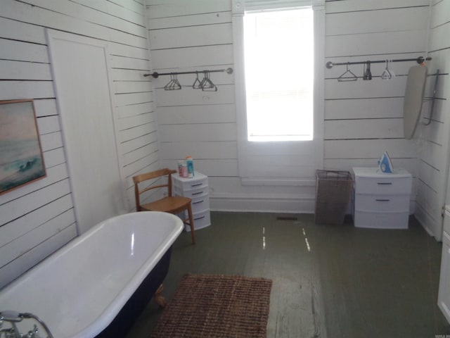 bathroom with a freestanding tub, wood finished floors, and wood walls