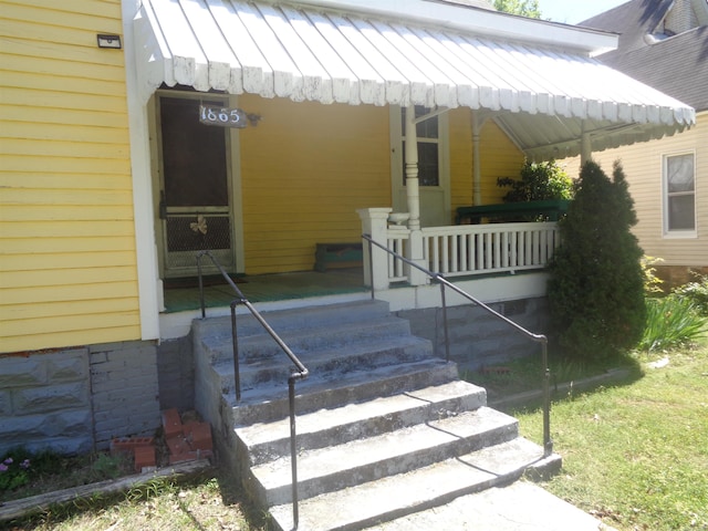 view of exterior entry with a standing seam roof, metal roof, and covered porch