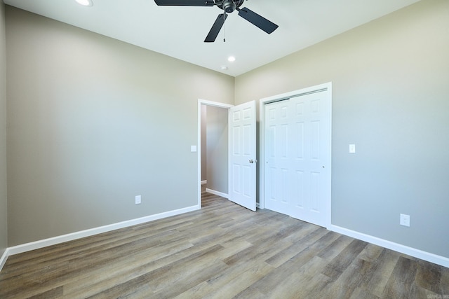 unfurnished bedroom featuring light hardwood / wood-style flooring, ceiling fan, and a closet