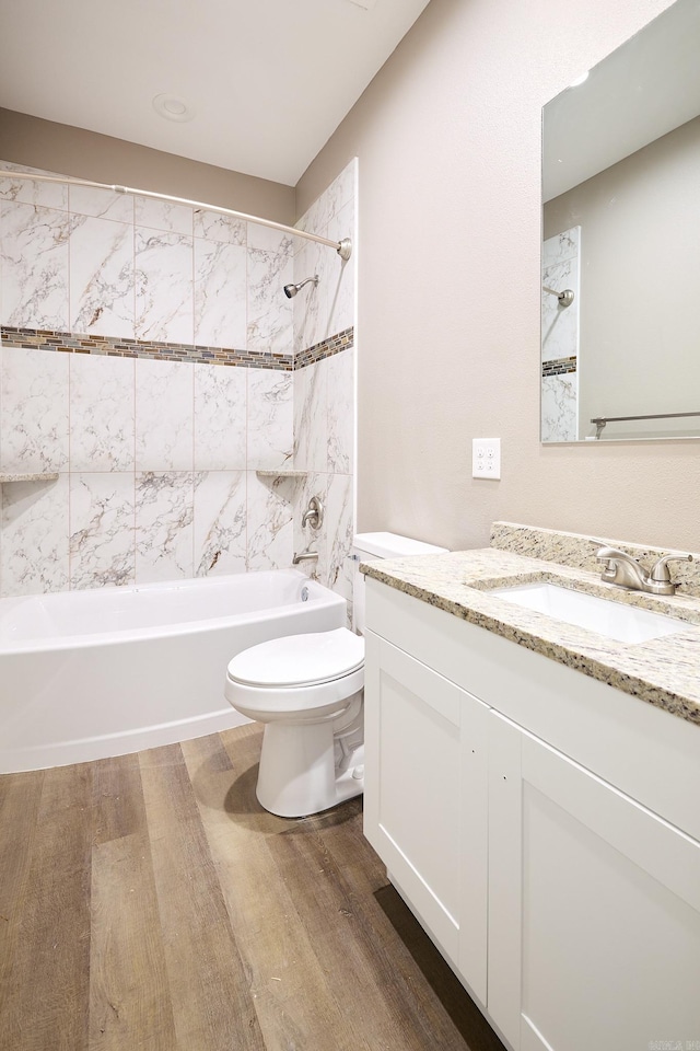 full bathroom featuring tiled shower / bath, vanity, toilet, and hardwood / wood-style floors