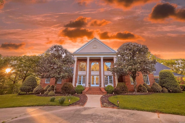 greek revival inspired property featuring french doors and a lawn