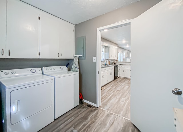 clothes washing area with sink, light hardwood / wood-style flooring, cabinets, and washer and clothes dryer