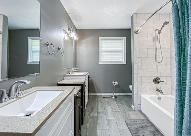 full bathroom featuring tiled shower / bath, plenty of natural light, vanity, and toilet