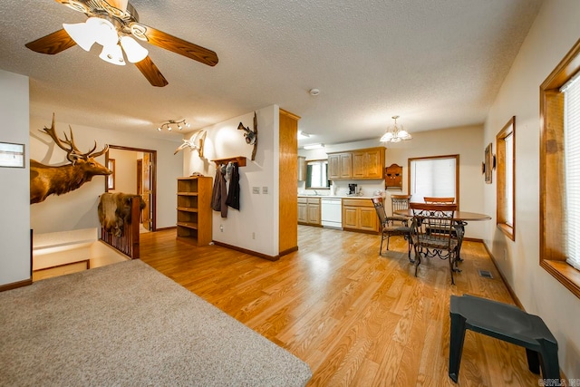 living room with ceiling fan with notable chandelier, a textured ceiling, and light hardwood / wood-style floors