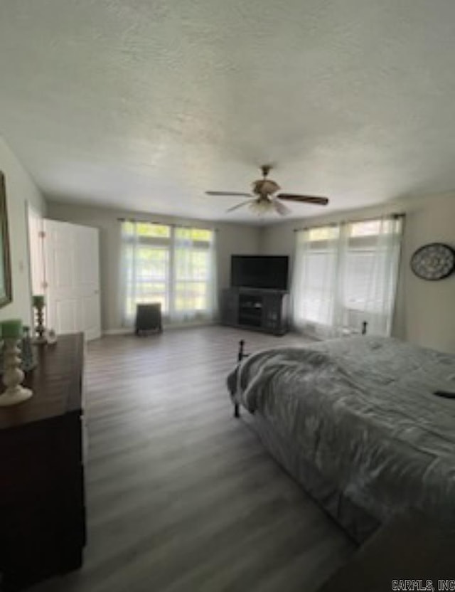 bedroom with hardwood / wood-style floors, ceiling fan, and a textured ceiling