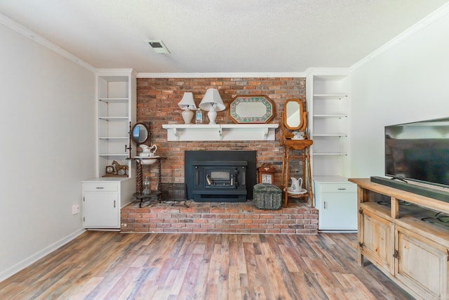 unfurnished living room featuring built in features, wood-type flooring, a textured ceiling, a fireplace, and ornamental molding