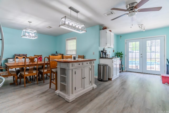 kitchen with ceiling fan, white cabinets, light hardwood / wood-style floors, hanging light fixtures, and french doors