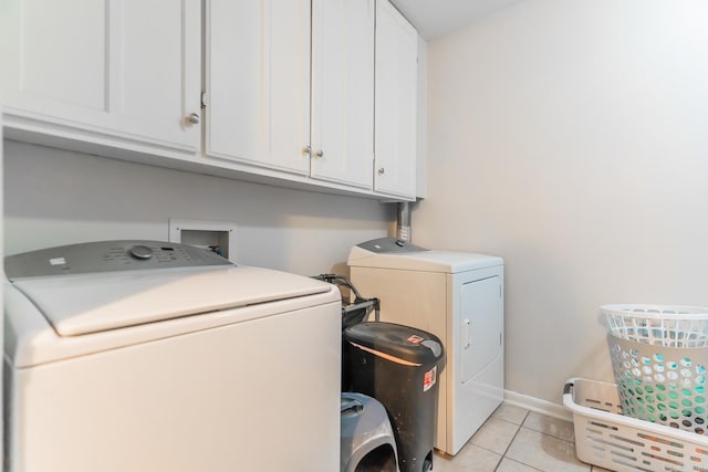 laundry room with cabinets, washing machine and dryer, and light tile flooring