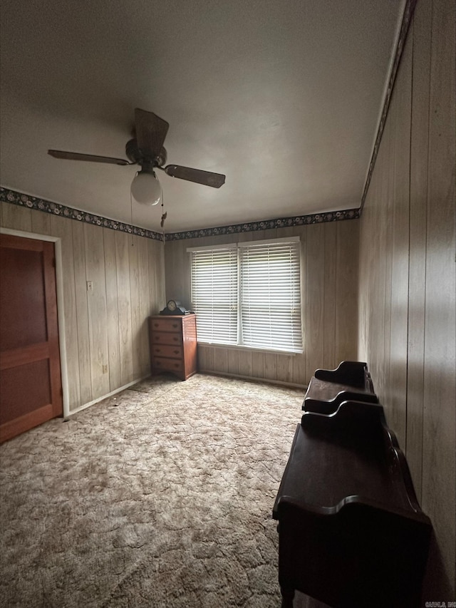 unfurnished room with wood walls, carpet floors, and ceiling fan