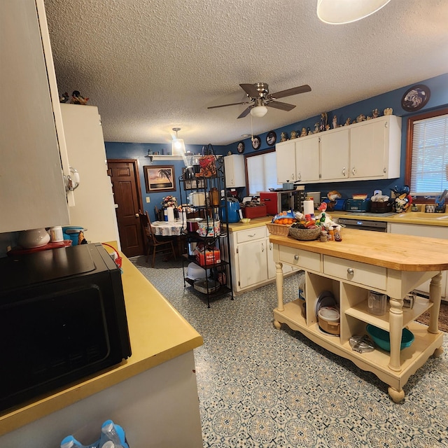 kitchen featuring white cabinets, wood counters, sink, ceiling fan, and a textured ceiling