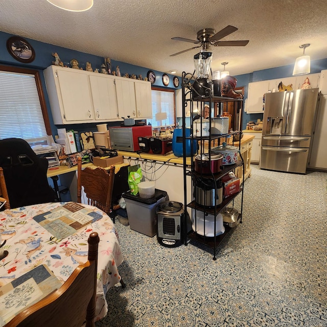 kitchen with stainless steel fridge with ice dispenser, ceiling fan, white cabinetry, and a textured ceiling