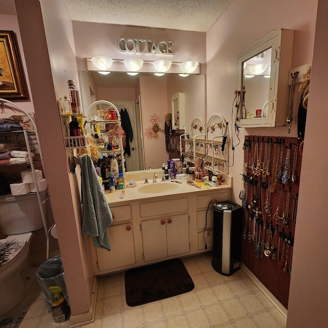 bathroom featuring tile flooring, oversized vanity, toilet, and a textured ceiling