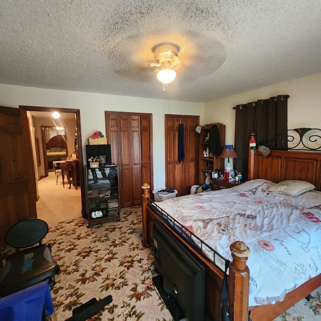 carpeted bedroom with ceiling fan and a textured ceiling