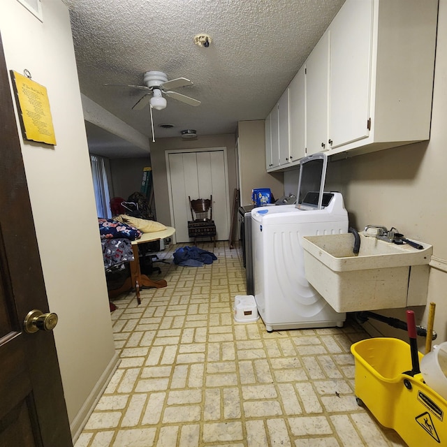 clothes washing area featuring ceiling fan, cabinets, a textured ceiling, sink, and independent washer and dryer