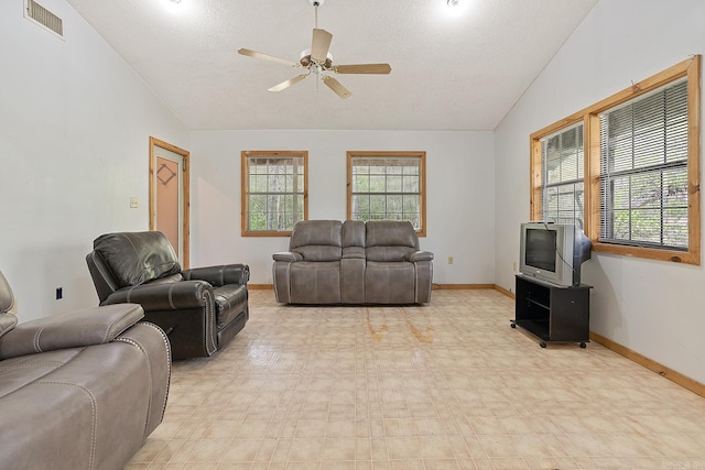 living room with a textured ceiling, ceiling fan, vaulted ceiling, and light tile flooring