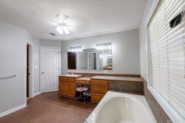 bathroom with ceiling fan, a textured ceiling, a relaxing tiled bath, tile floors, and vanity