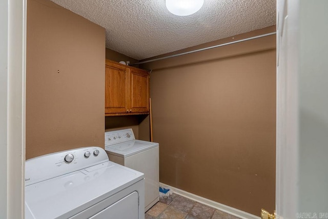 clothes washing area with light tile floors, cabinets, separate washer and dryer, and a textured ceiling