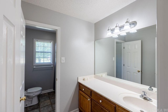 bathroom with toilet, tile flooring, vanity, and a textured ceiling